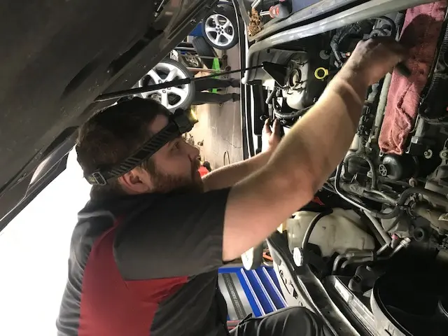 Automotive technician working under the hood of a vehicle